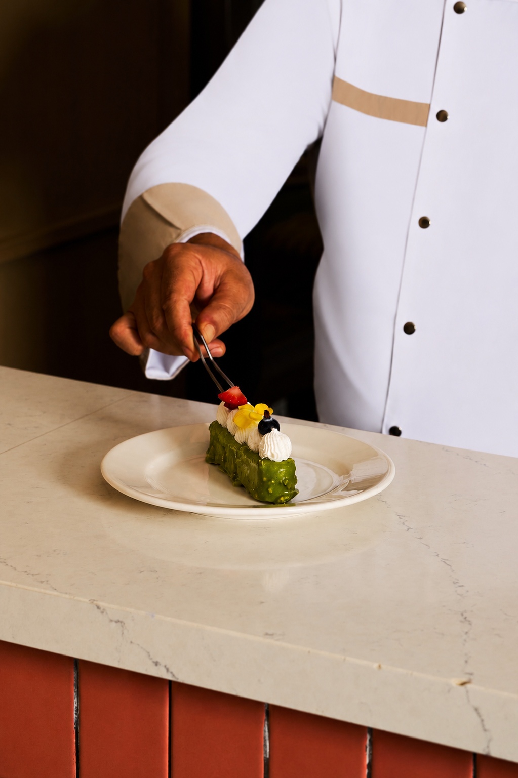 Chef plating a pistachio dessert at the table