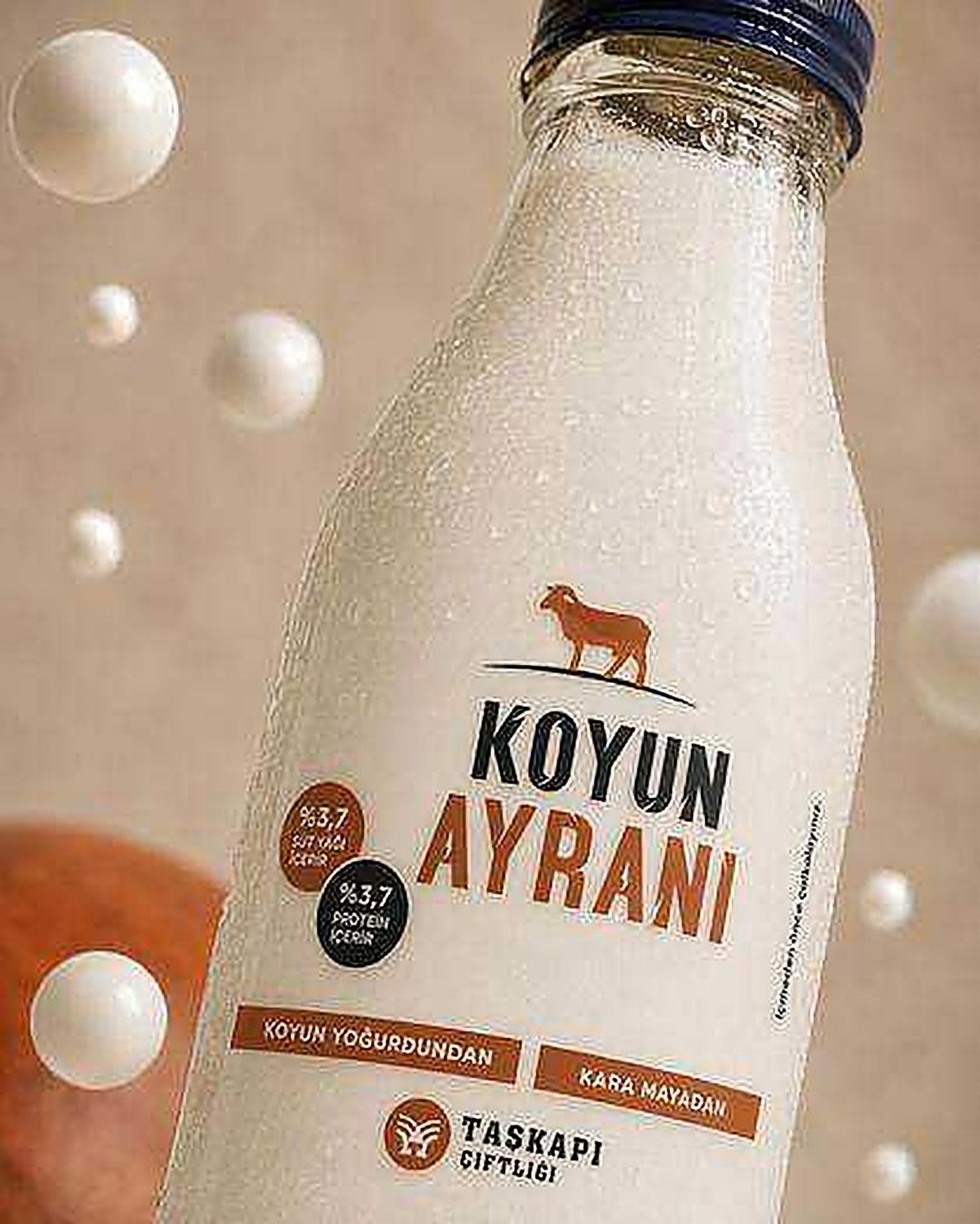Close-up of a Taşkapı Çiftliği ayran bottle with water droplets and floating bubbles